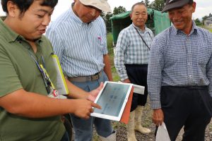 ＪＡ職員が生産者に、水田の日射量や水量などのデータをタブレット端末で説明